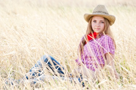 Portrait of a young beautiful girl-cowboy in the dried grassの写真素材