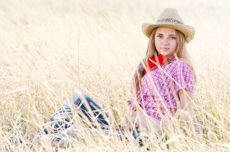 Portrait of a young beautiful girl-cowboy in the dried grassの写真素材