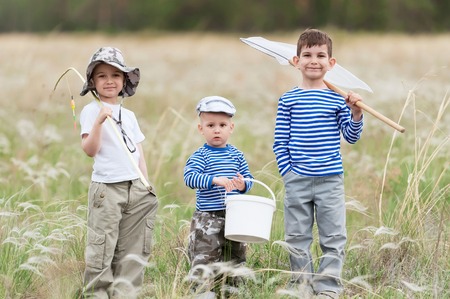 Three boys - fishermen on a meadow at the catchの写真素材