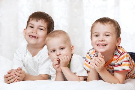 Portrait of happy young boys on the bedの写真素材