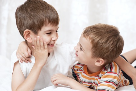 Portrait of happy young boys on the bedの写真素材
