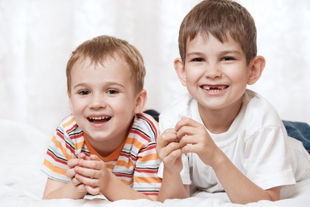 Portrait of happy young boys on the bedの写真素材