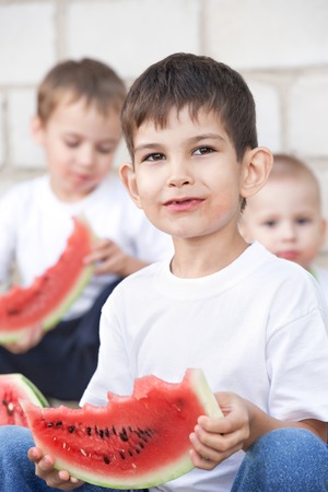 little boys with a big watermelon on the porch on a summer dayの写真素材