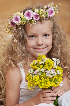 Portrait of a young girl with flowers in the hayの写真素材
