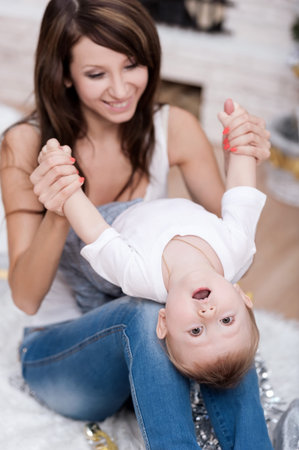 Happy mother with her son by the fireplace under the Christmas tree