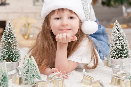 Little girl with toys on the carpet under the Christmas treeの写真素材