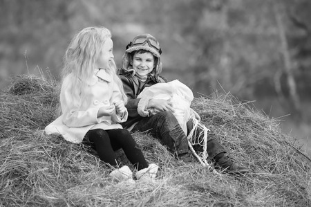 Boy with a girl sitting on a haystack with a parachute in the autumn sunny dayの写真素材