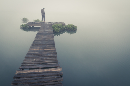 man taking photo when sunrise on wood pierの写真素材