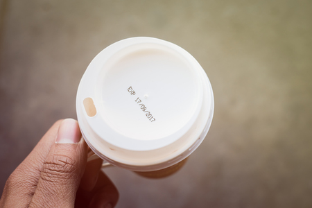hand holding coffee cup with label expirationの写真素材