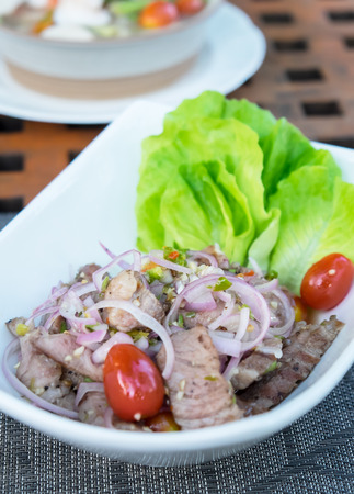 Thai food.spicy grilled pork salad served with vegetableの写真素材