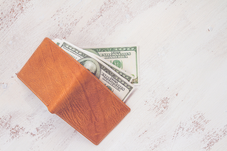 Dollars money in a leather wallet on white wooden board. top viewの写真素材