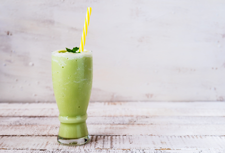 a glass of green tea smoothie on white wooden boardの写真素材