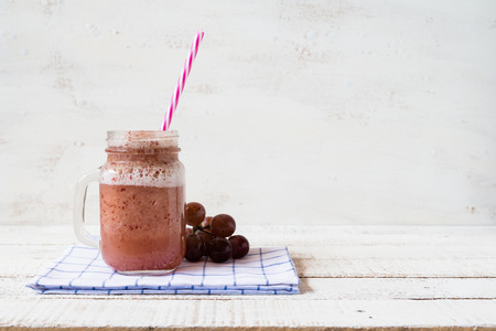 a jar of strawberry and grape berry smoothie on white wooden boardの写真素材