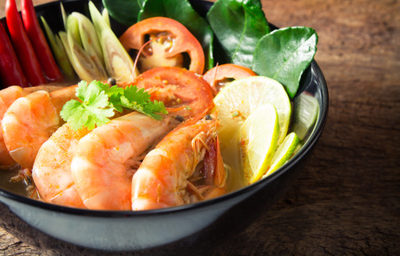 thai food. closeup tom yum goong, spicy sour soup with prawn on black bowlの写真素材