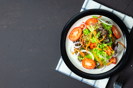 homemade vegetable salad tomato, carrot, onion, spinach, and lettuce on black board. top viewの写真素材