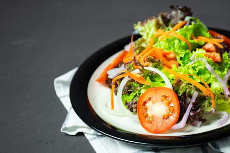 vegetable salad tomato, carrot, onion, spinach, and lettuce on black board.の写真素材