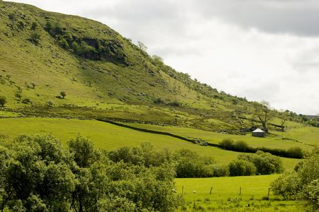A green welsh hillside and valley under a dark skyの写真素材