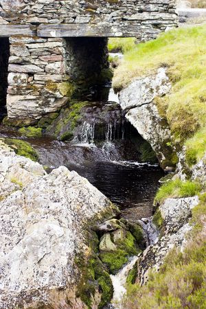 A dark waterfall under a typical slate bridge in the welsh high moorlandの写真素材