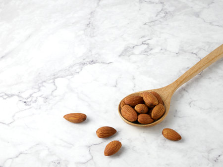 Almonds in wooden spoon on marble texture background.の写真素材