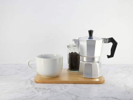 Coffee maker moka pot and a cup on marble  table.