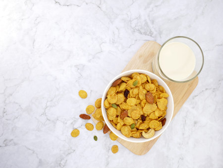 Grains cornflakes in bowl with milk glass on marble background.