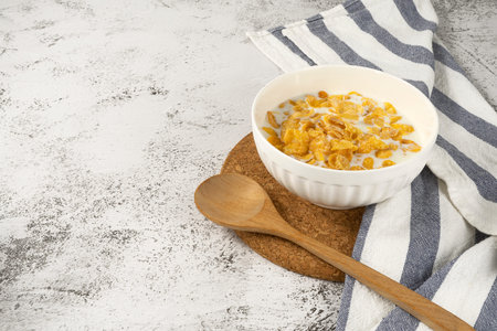 Corn flakes and milk in bowl on table