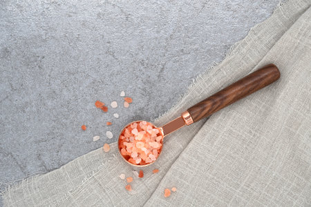 Himalayan pink salt in a spoon and cloth on stone texture backgroundの写真素材