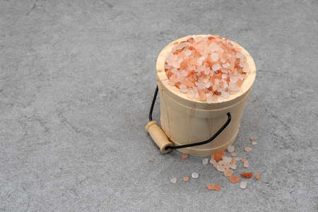 Himalayan pink salt in a wooden bucket on stone texture backgroundの写真素材