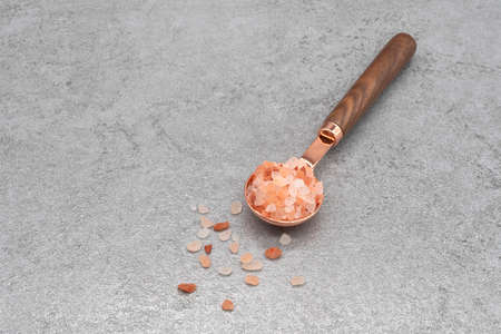 Himalayan pink salt in a spoon on stone texture backgroundの写真素材