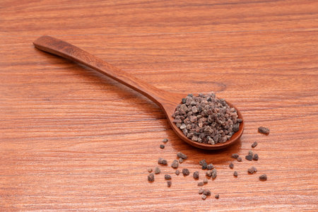Himalayan black salt in a wooden spoon on wooden background