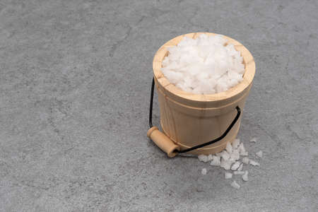 Sea salt in a wooden bucket on stone texture backgroundの写真素材
