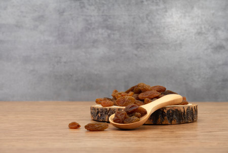 Raisins and wooden tray on wooden texture background. Dry raisins. Bulk raisins grains.の写真素材