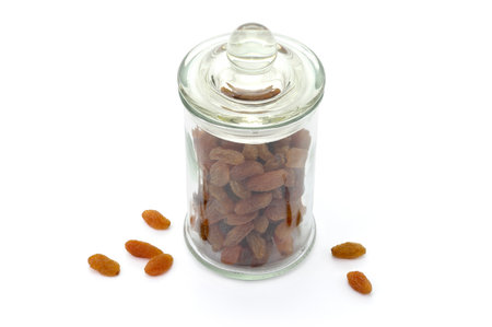 Raisins in glass jar isolated on white background. Dried seedless grapes. Healthy nutrition with fruits. Dried fruit as healthy snack.の写真素材