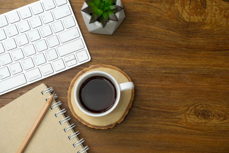 Top view above of office desk table with keyboard computer and coffee. Business and finance concept. Workplace. Flat lay with blank copy space. Wooden texture.の写真素材