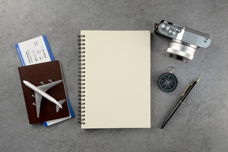 Passport with boarding pass and note book and camera on stone texture background. Tourism and travel concept. Top view. Flat lay.の写真素材