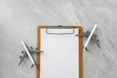 Paper board with airplane on stone texture background. Tourism and travel concept. Top view. Flat lay.の写真素材