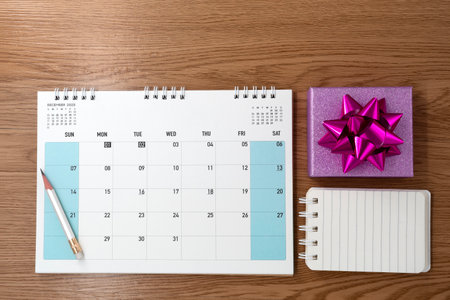 Gift box with calendar on wooden texture background. Planning. Flat lay. Top view.の写真素材