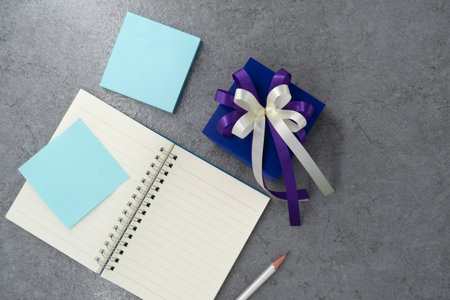 Gift box with note book on stone texture background. Planning. Flat lay. Top view.の写真素材