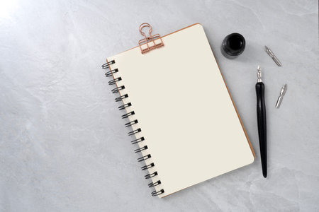 Blank book with dip pen on stone texture background. Writer workplace concept.の写真素材
