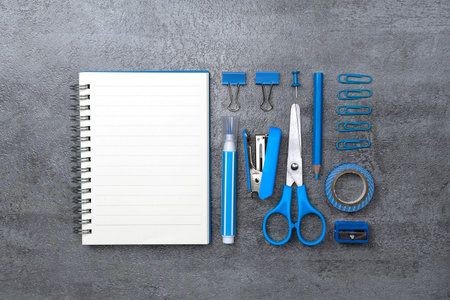 Notebook and blue stationery on stone texture background. Work desk space