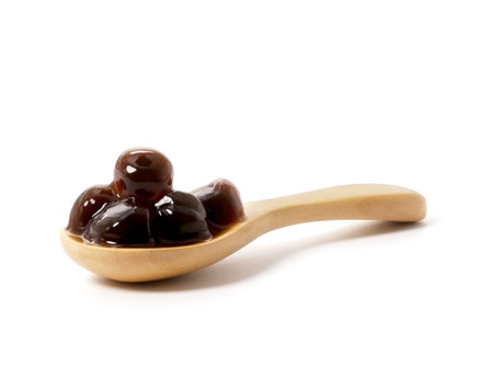 Brown sugar pearls bubble in wooden spoon isolated on white backgroundの写真素材