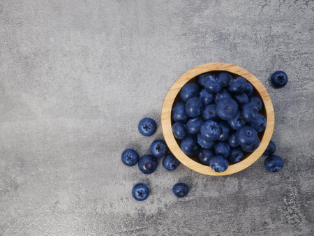 Blueberries in wooden bowl on stone texture backgroundの写真素材