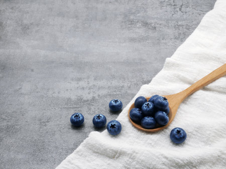 Blueberries in wooden spoon with cloth on stone texture backgroundの写真素材