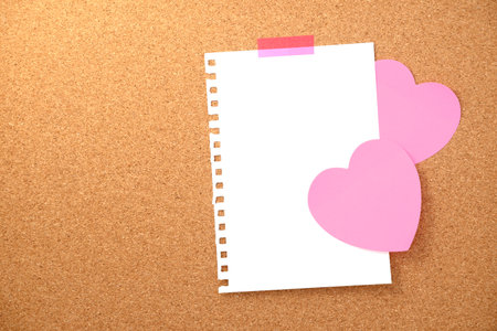 Heart shaped note and paper note on brown cork board texture backgroundの写真素材
