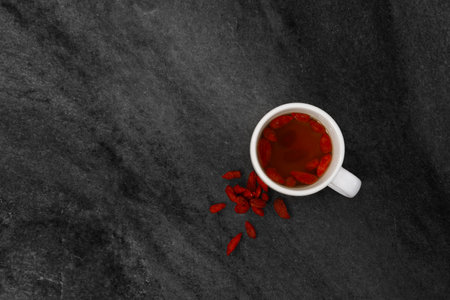 Cup of tea with goji berries on black stone texture backgroundの写真素材
