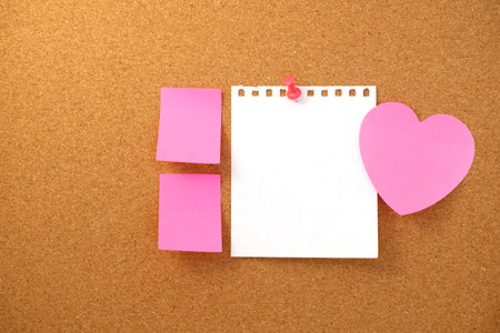 Heart shaped note and paper note on brown cork board texture backgroundの写真素材