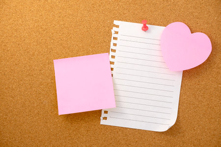 Heart shaped note and paper note on brown cork board texture backgroundの写真素材
