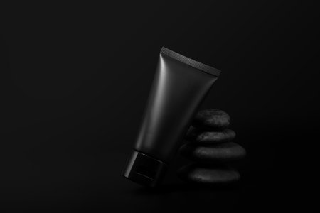 Black plastic cream tube with stone for mockup on black background. Selective Focus.の写真素材
