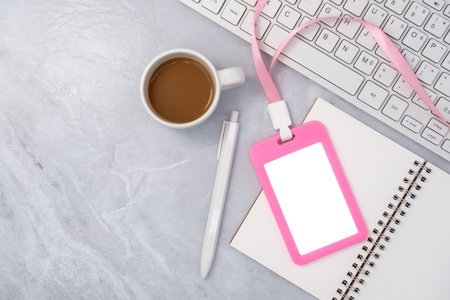 Pink plastic badge with keyboard and coffee on white stone texture background. Template designed for employees of companyの写真素材