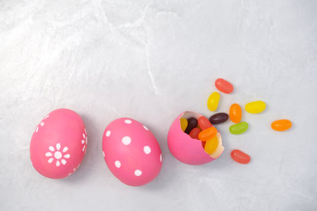 Cracked pink Easter egg with candy on stone texture background. Painted eggs. Egg Holiday